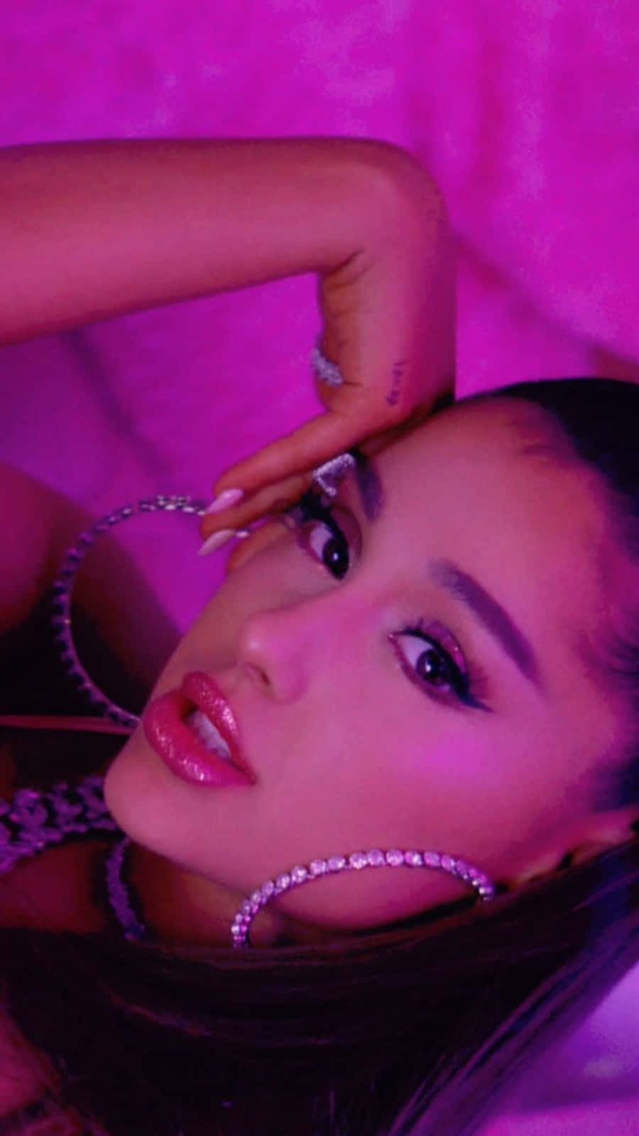 Ariana Grande 在粉紅色燈光肖像中佩戴鑽石耳環。