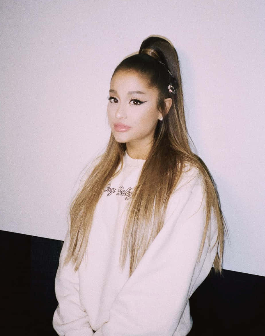 Ariana Grande 身穿白色衛衣，頭髮紮成高馬尾。