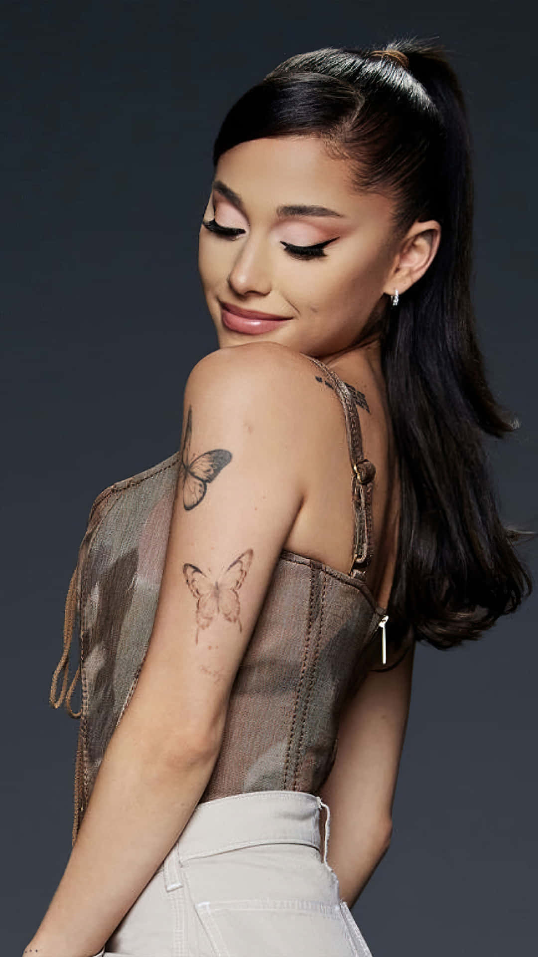 Ariana Grande 在工作室肖像中手臂上有蝴蝶紋身。
