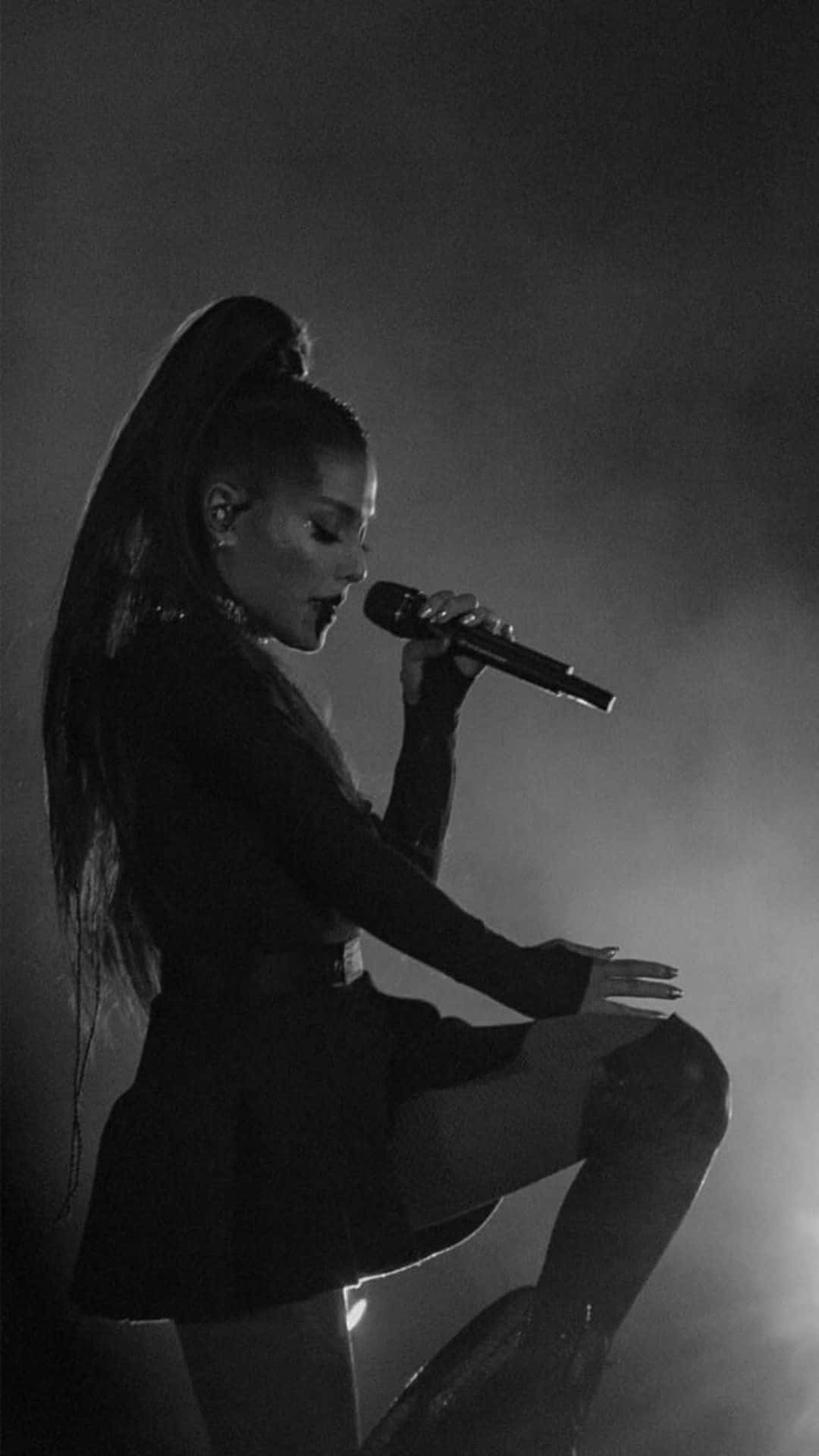 歌手Ariana Grande 在舞台上手持麥克風並有煙霧效果。 — 愛莉安娜·格蘭德 壁紙