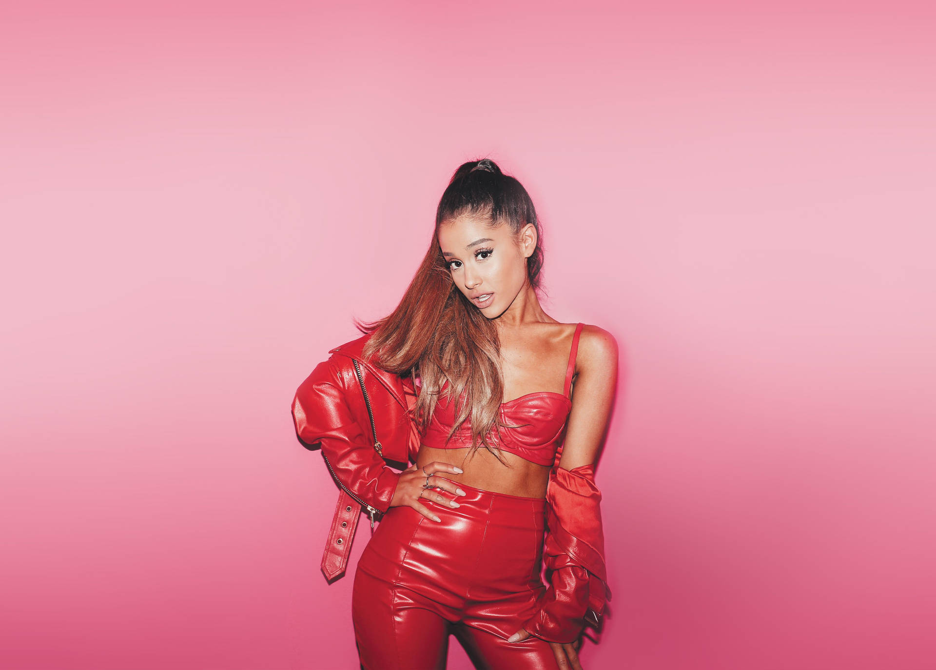 Ariana Grande 穿著紅色皮革套裝在粉色背景前