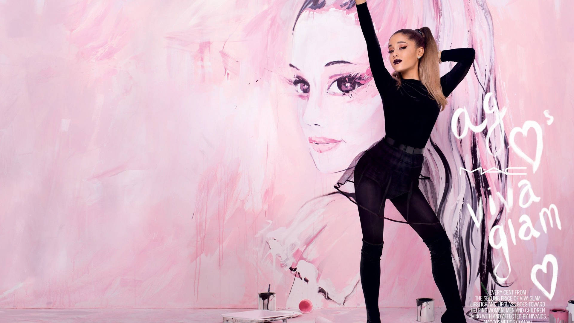Ariana Grande 身穿黑色服裝，在粉紅色壁畫前擺姿勢，壁畫上畫有她的臉。