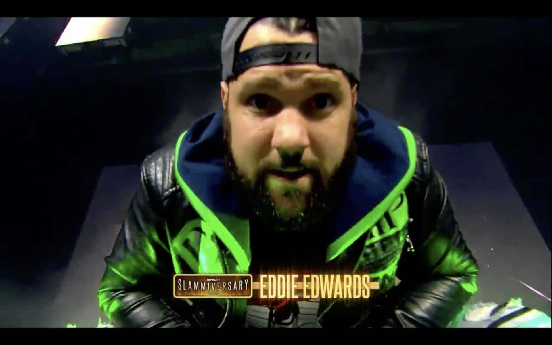 摔角手 Eddie Edwards 身穿帶有螢光綠色飾邊的黑色皮褸，凝視著鏡頭。