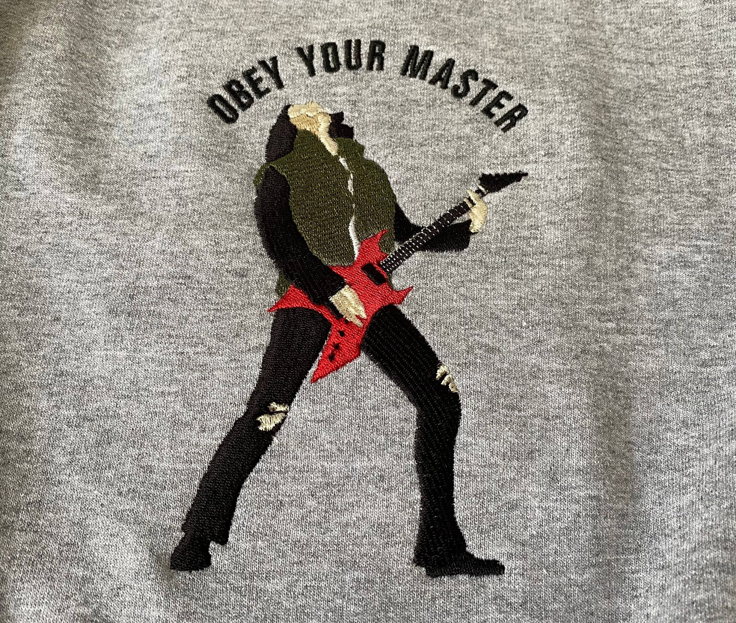 愛迪·蒙森彈吉他並寫著「服從你的主人」 壁紙 — 繡有紅色結他及'OBEY YOUR MASTER'文字的龐克搖滾者圖案，位於混色灰衛衣布料上。
