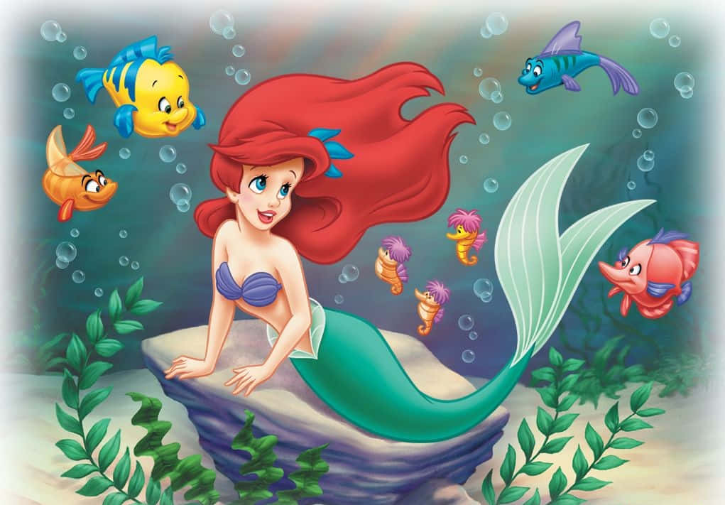 愛麗兒夢想探索神奇的海底世界 壁紙 — 人魚公主艾莉奧擁有一頭飄逸的紅髮，坐在岩石上，被色彩繽紛的魚和氣泡環繞的水底場景。