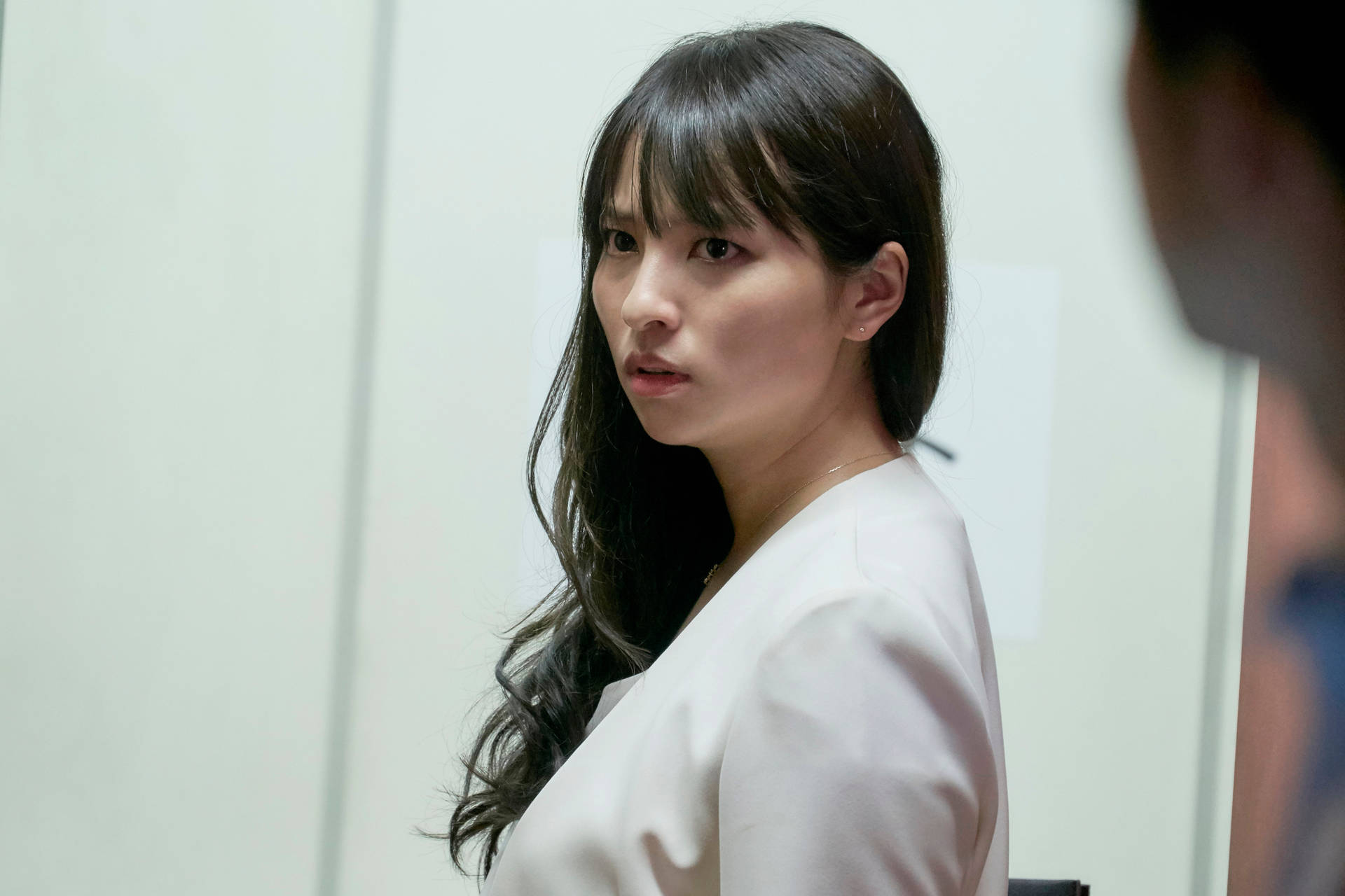 身穿白色襯衫的女子在室內回頭看