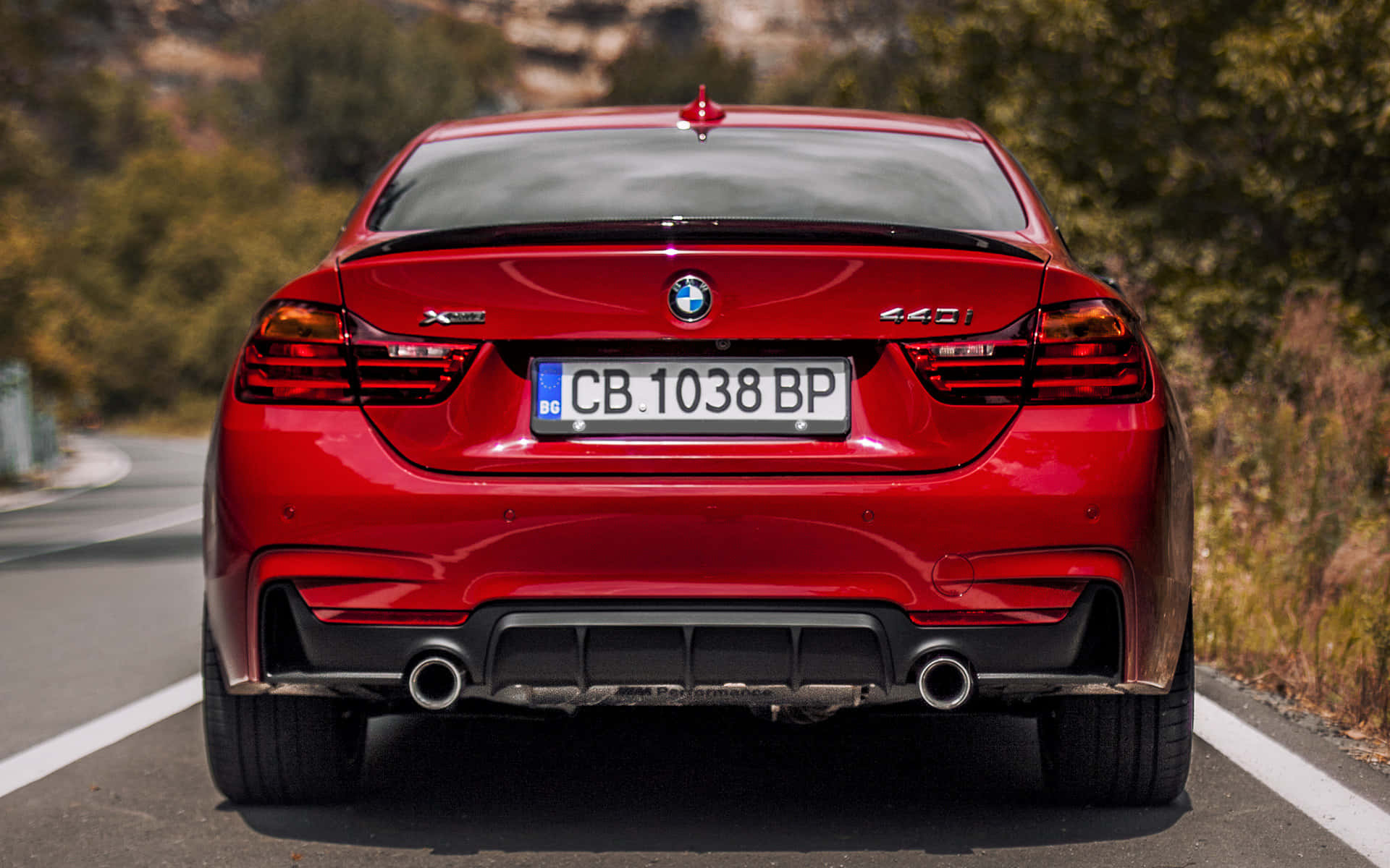 紅色BMW 440i跑車在日落時分行駛在森林道路上。