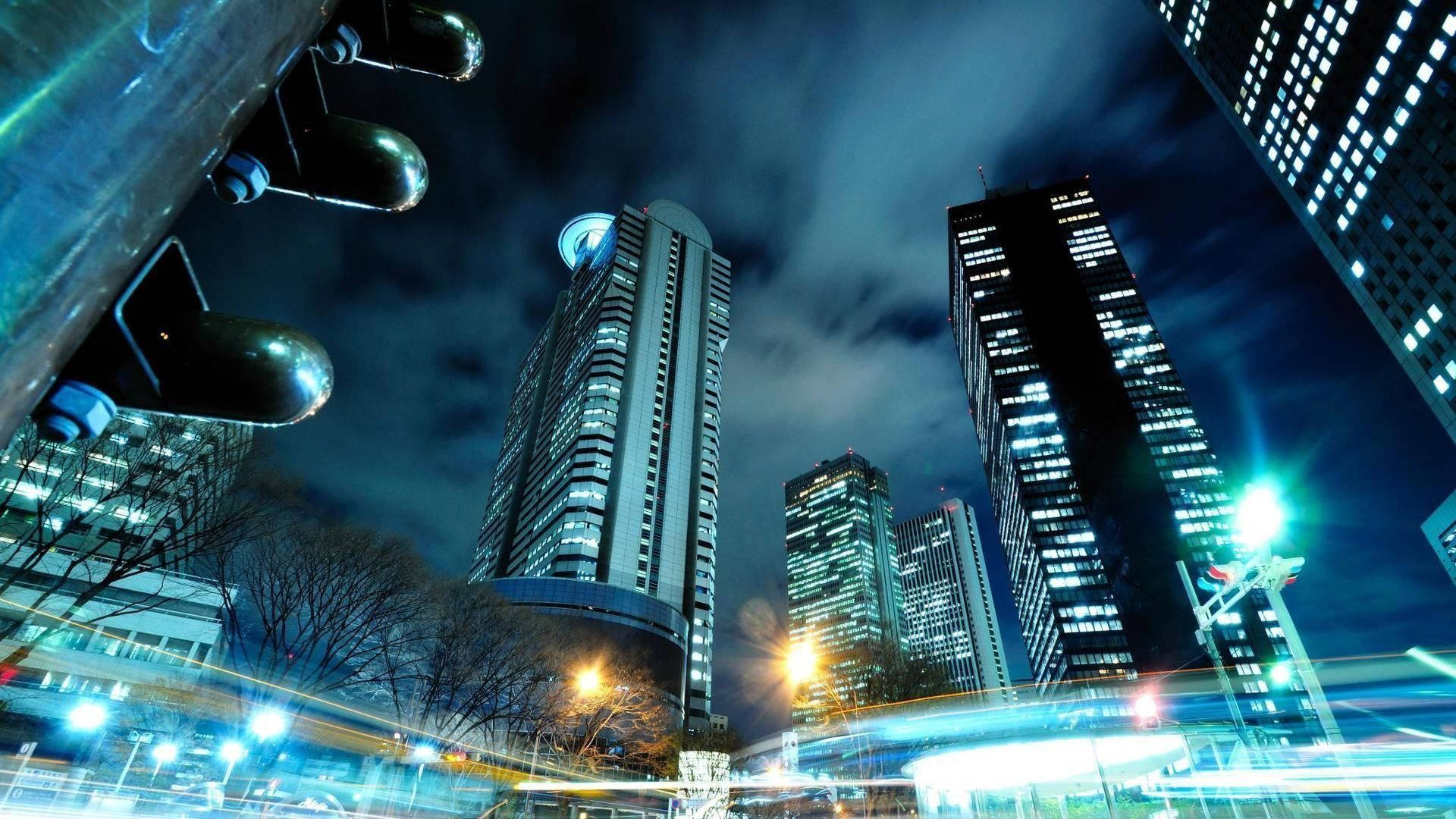 夜間城市景觀，燈火通明的摩天大樓和移動車輛的光軌。
