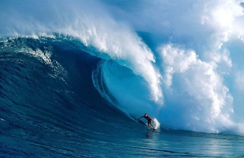 感受夏日海風，衝浪完美浪花。 壁紙 — 一位衝浪者在明亮日光下騎乘巨大碧綠色海浪的浪管。