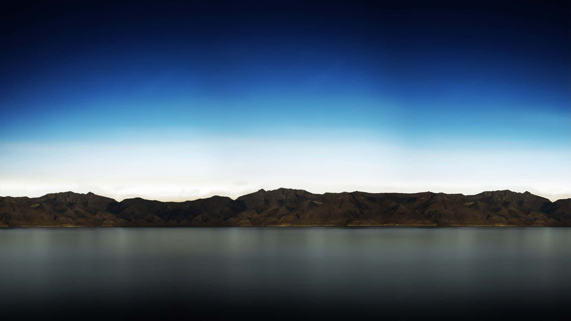 剪影般的山脈在暮色天空下倒映在靜止的水面上。