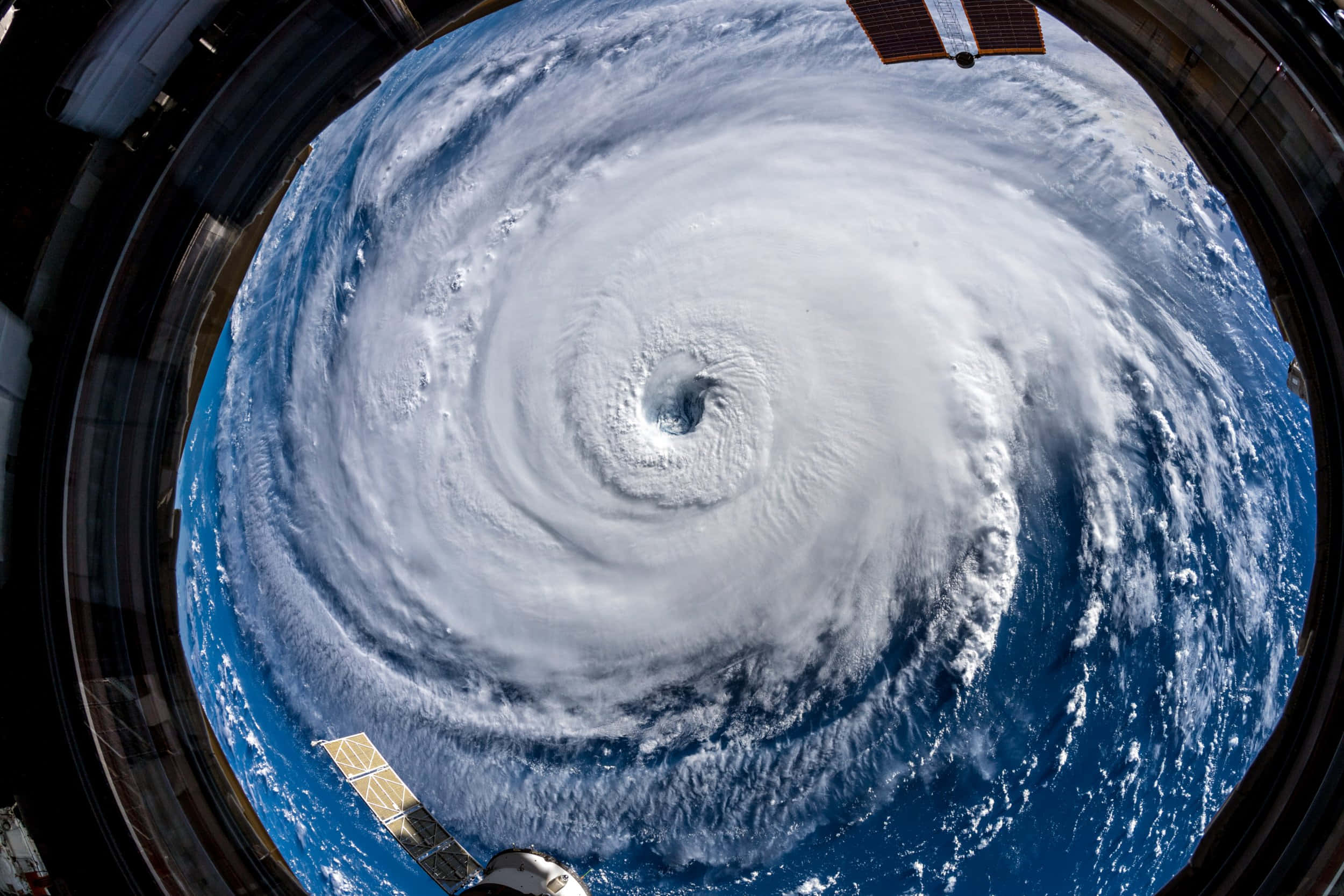 感受強烈颶風的威脅 壁紙 — 從太空透過太空船窗戶看到的巨大颶風，太陽能板清晰可見。