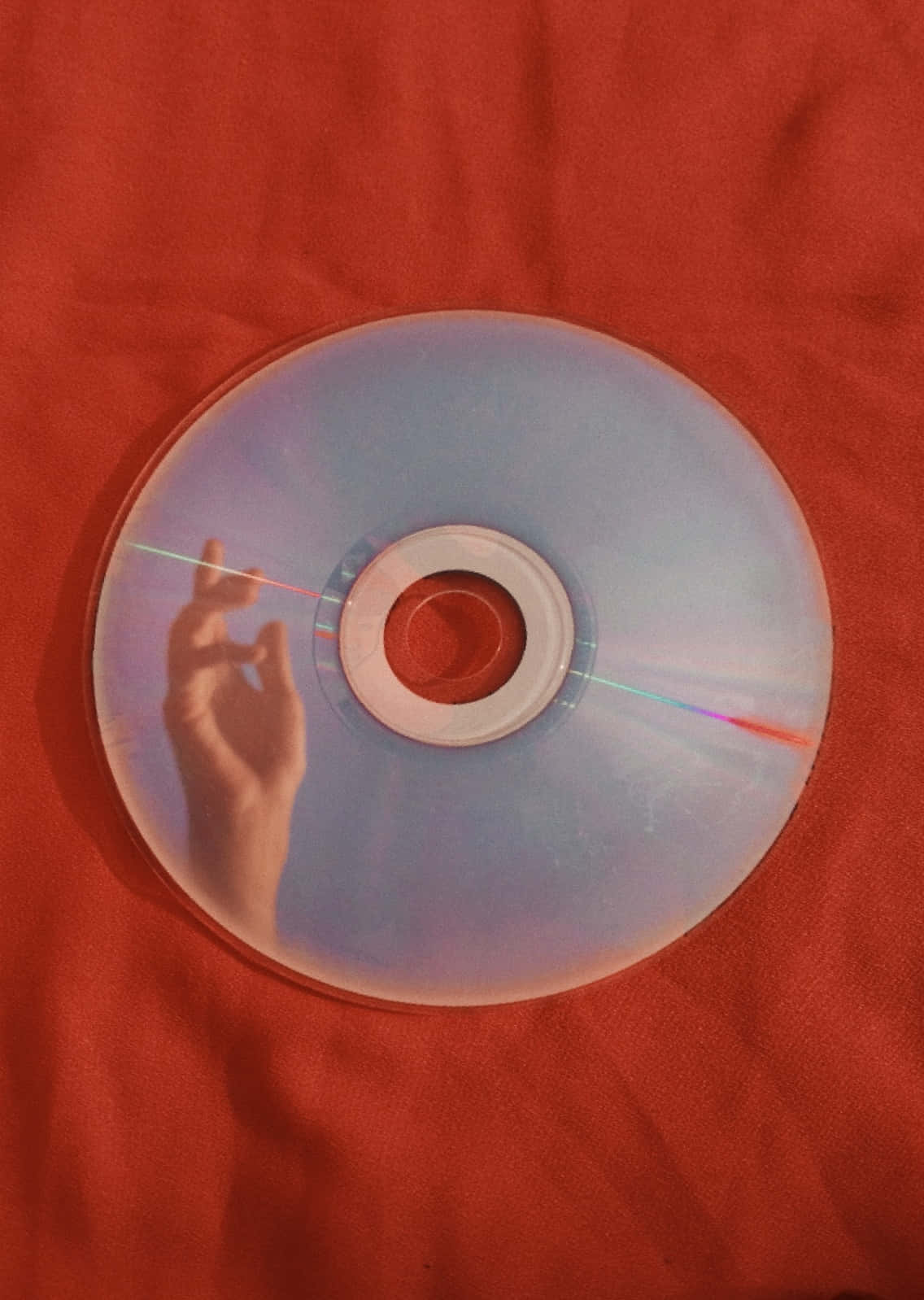 手影投射在CD上，背景為紅色布料