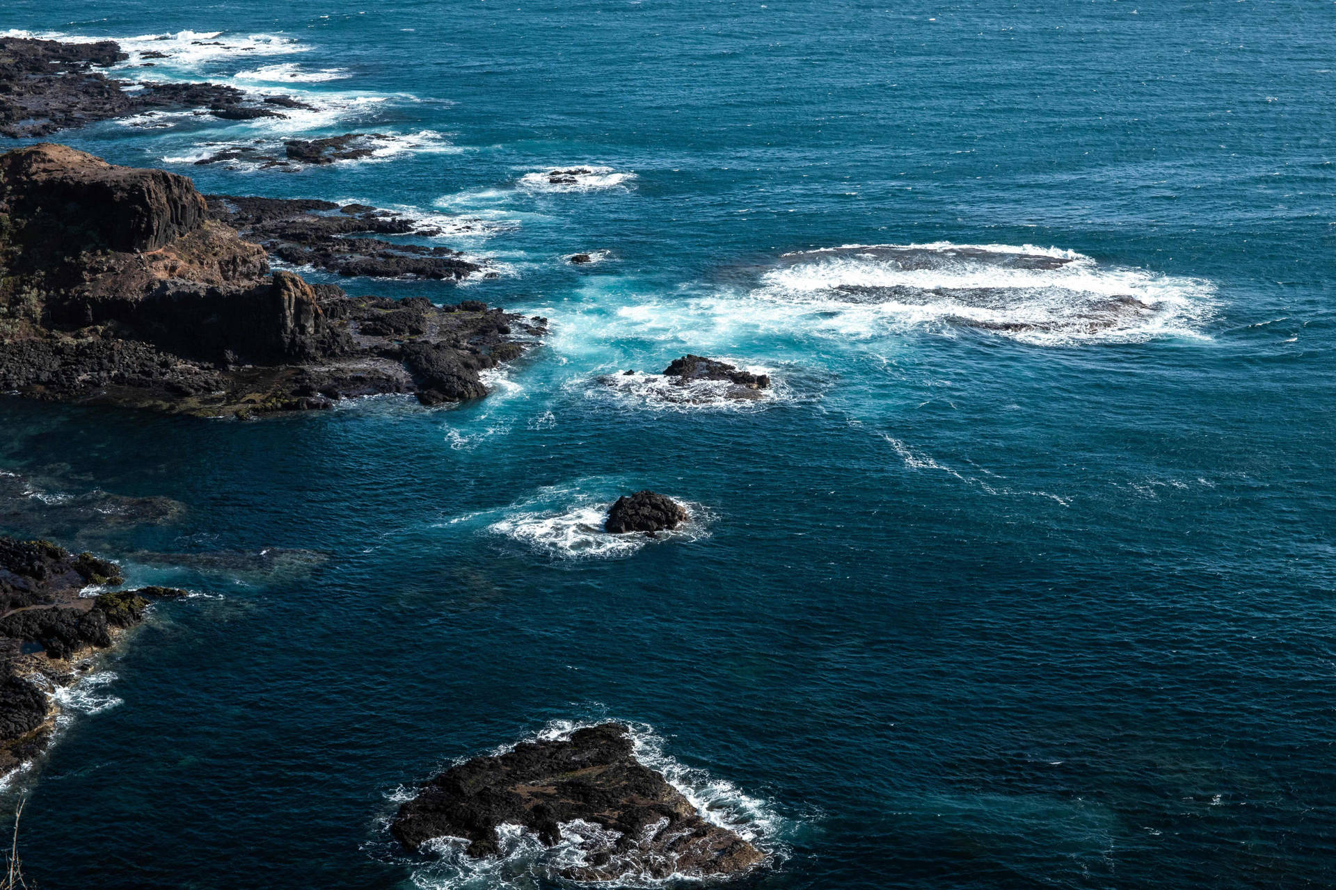 崎嶇的沿海岩石，海浪拍打形成白色泡沫圖案。