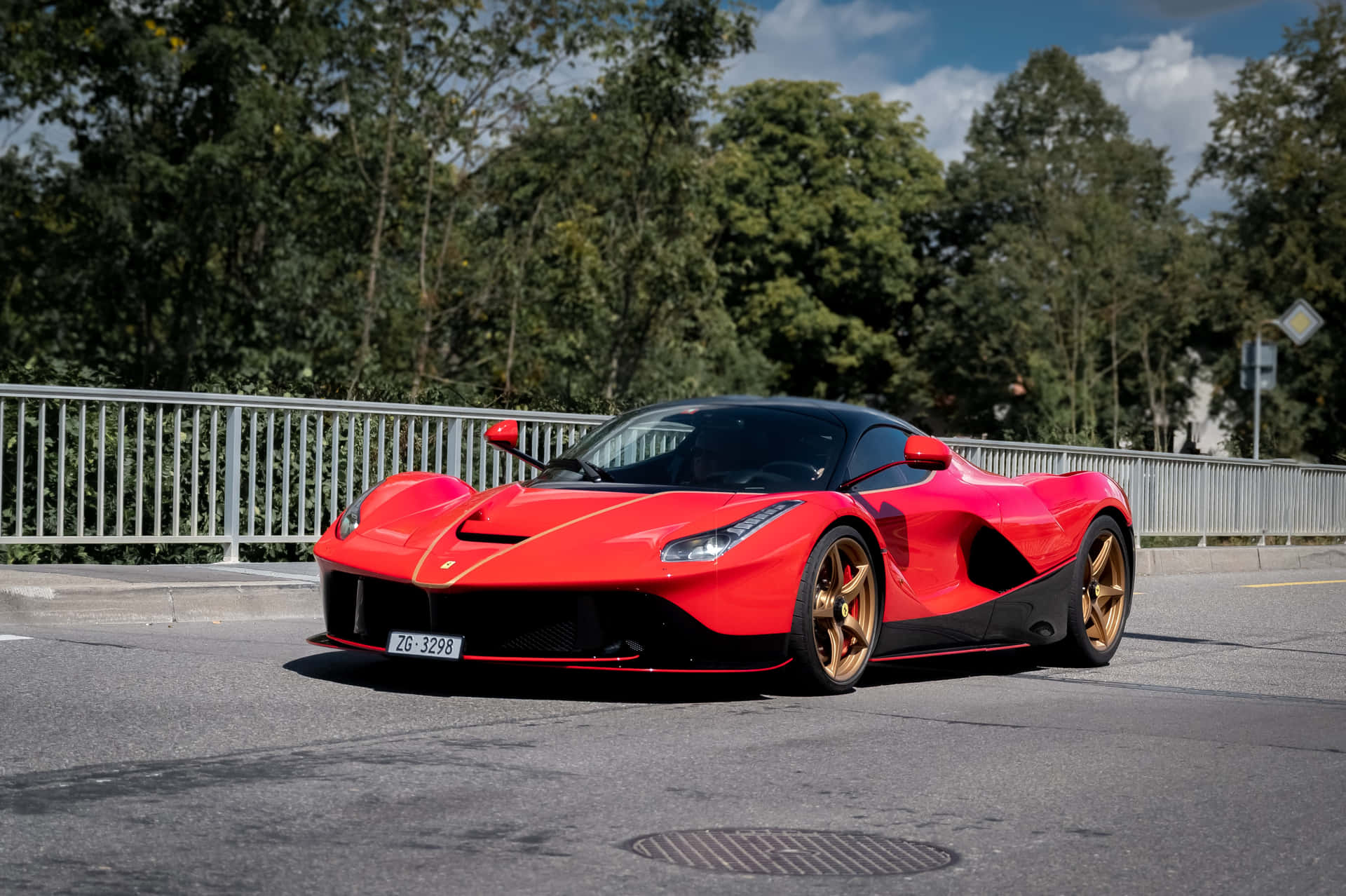 紅色法拉利 LaFerrari 配金色輪胎，停泊在樹旁的道路上。