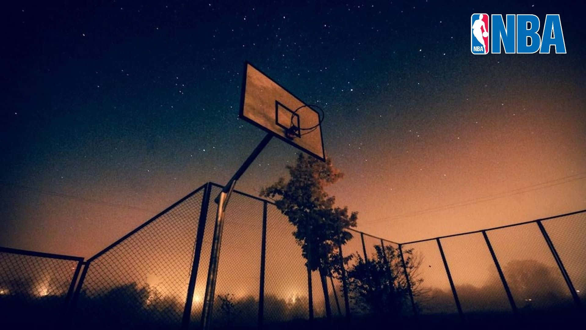 一個籃球框在繁星點點的夜空下，帶有橙色光芒。