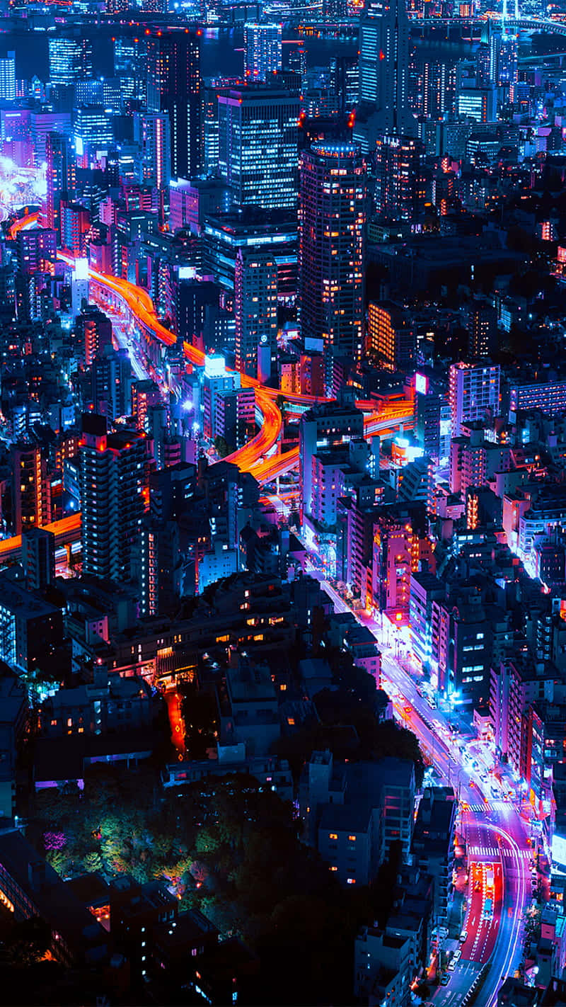 發光霓虹城市的夜間鳥瞰圖，有繁忙的高速公路和高樓大廈。
