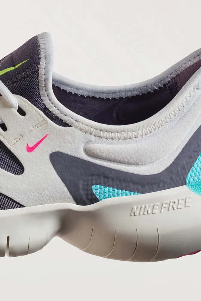 Nike Free 跑鞋特寫，帶有灰色、粉紅色和藍綠色點綴。