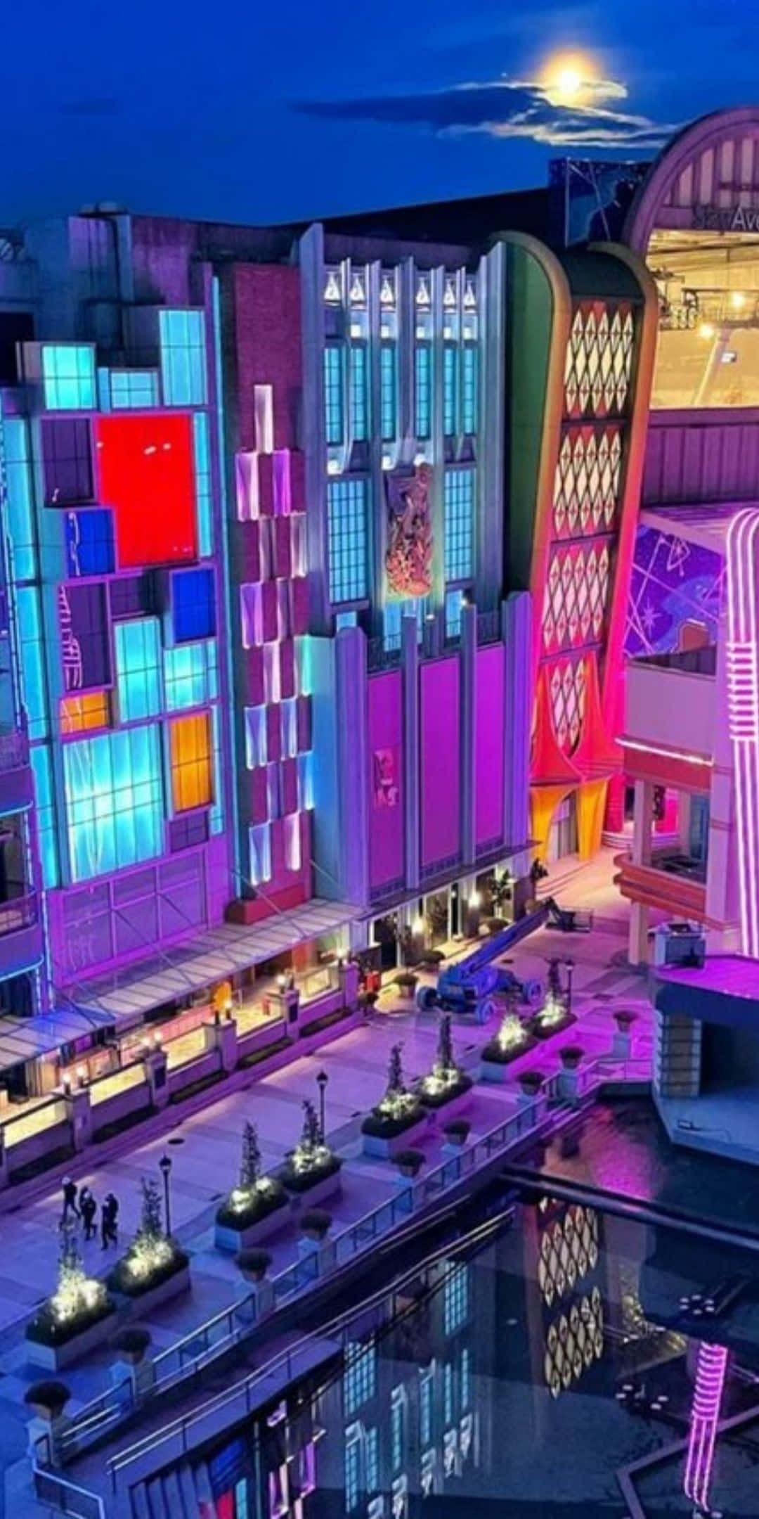 感受酷感氛圍 壁紙 — 充滿活力的霓虹燈建築在月光下的夜空下閃耀，倒映在下方平靜的水道上。