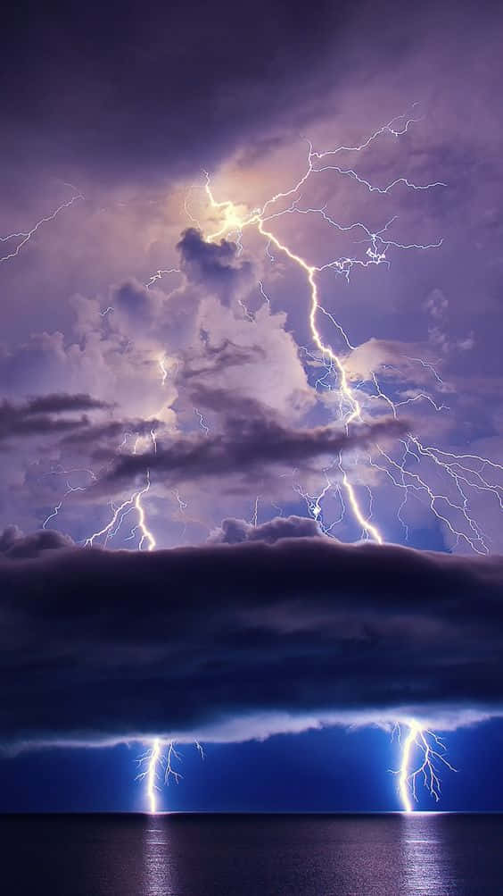 強大的閃電照亮了深紫色天空下的暴風雨海洋。