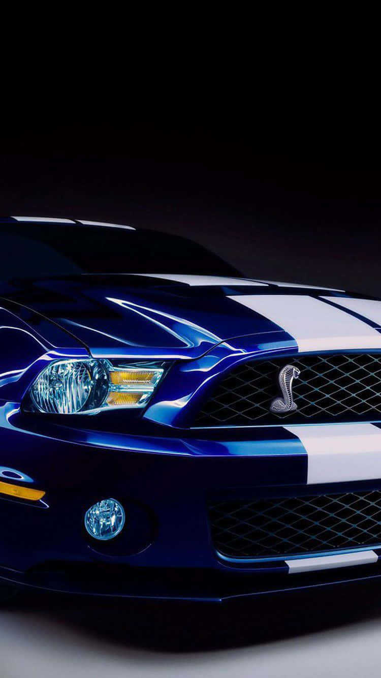 藍色 Shelby Mustang 帶有白色條紋和眼鏡蛇標誌，在攝影棚燈光下。