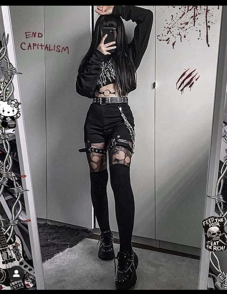 穿著哥德服裝的人在帶有抗議藝術和鐵絲網裝飾的房間裡擺姿勢。