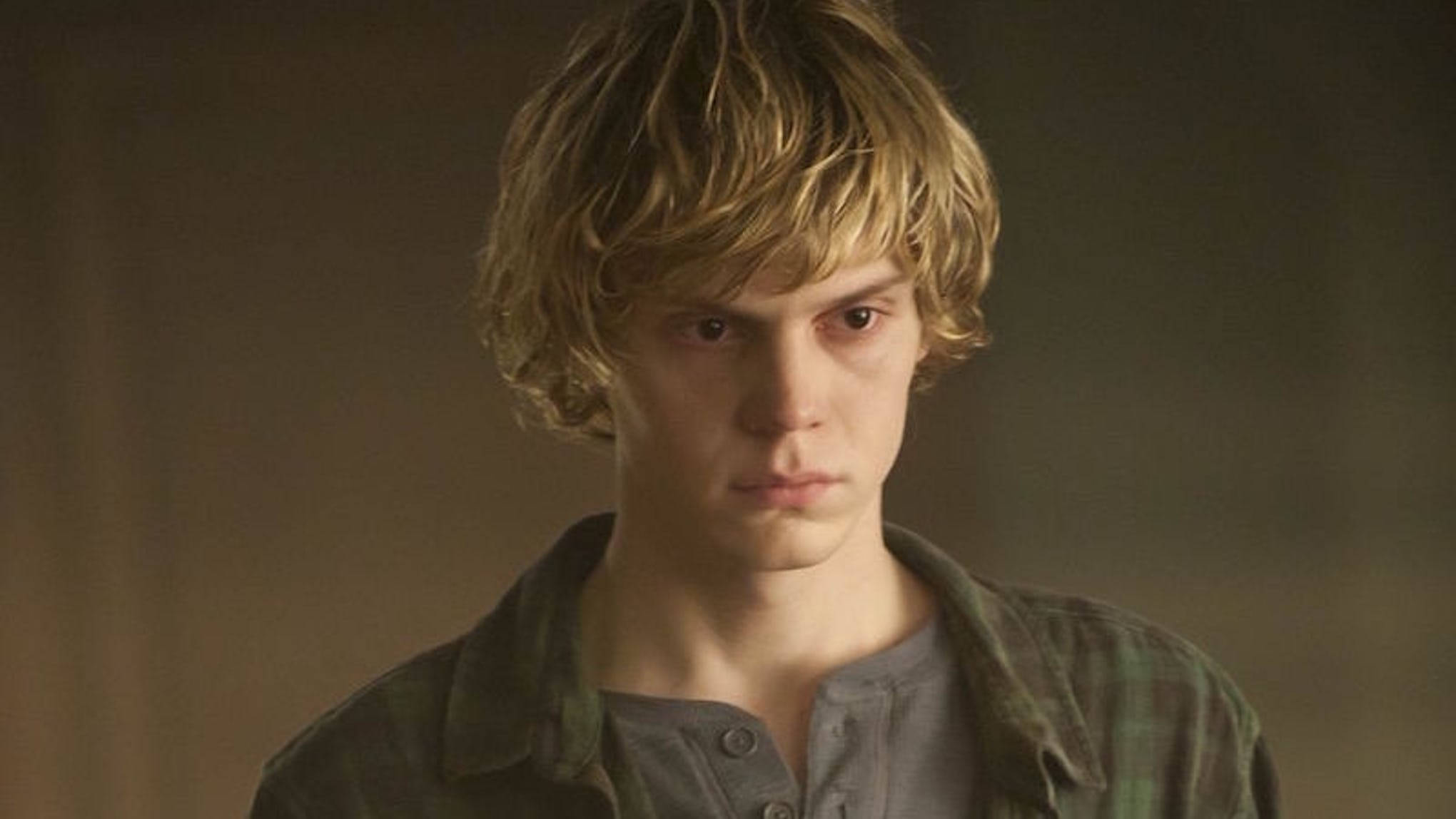 感性 Tate Langdon 壁紙 — 一個頭髮蓬鬆的金髮年輕男子，穿著灰色亨利衫外搭格仔恤衫，專注地向前凝視。