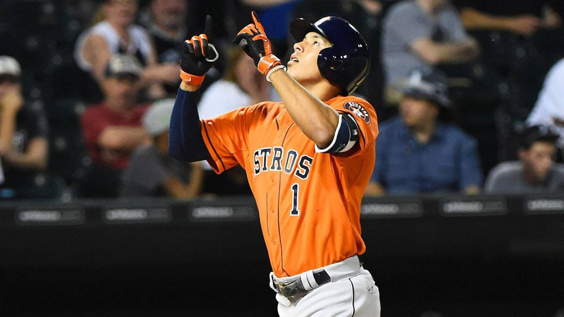 身穿橙色Astros球衣的棒球選手在夜晚手指向上慶祝。