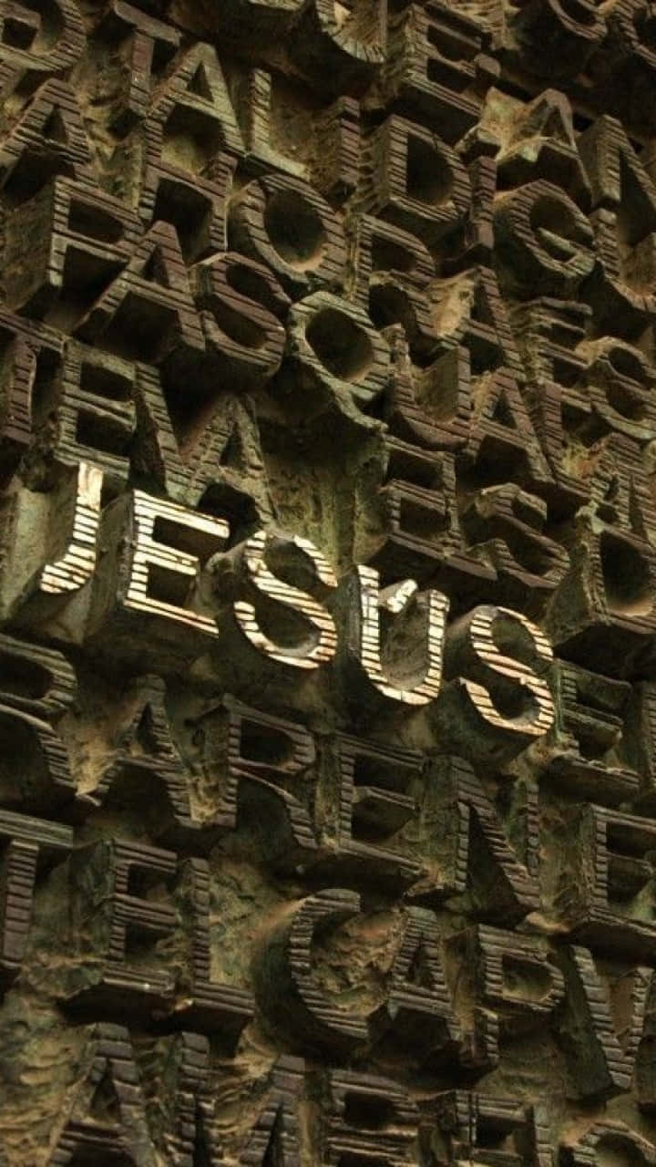 雕刻石牆，凸起字母拼出JESUS，以金色照亮。