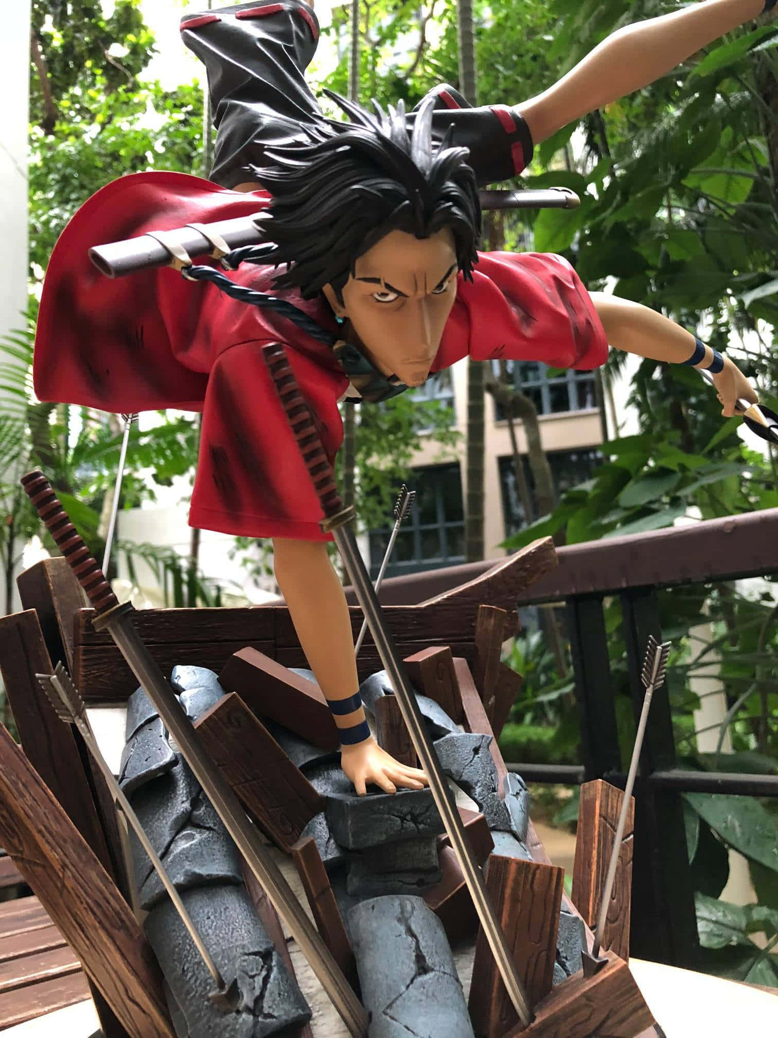 慶祝兩位武士的冒險旅程 壁紙 — 身穿紅色斗篷的劍士在茂密綠葉中動態跳躍的動漫人偶。