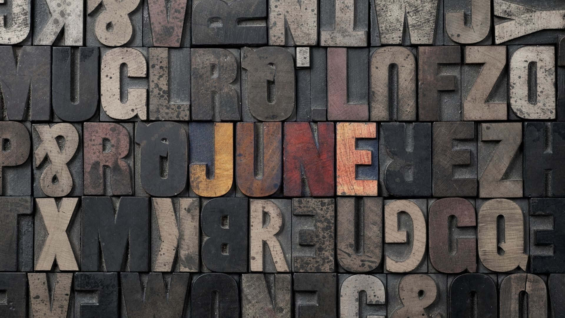 復古木製活字塊拼出 june，帶有磨損質感。