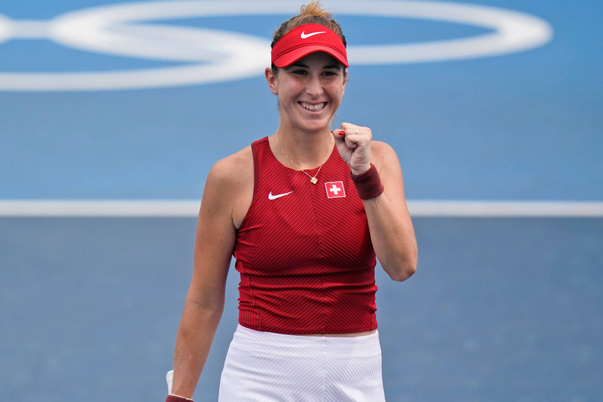 女性網球選手在藍色球場上身穿紅白裝備慶祝勝利。