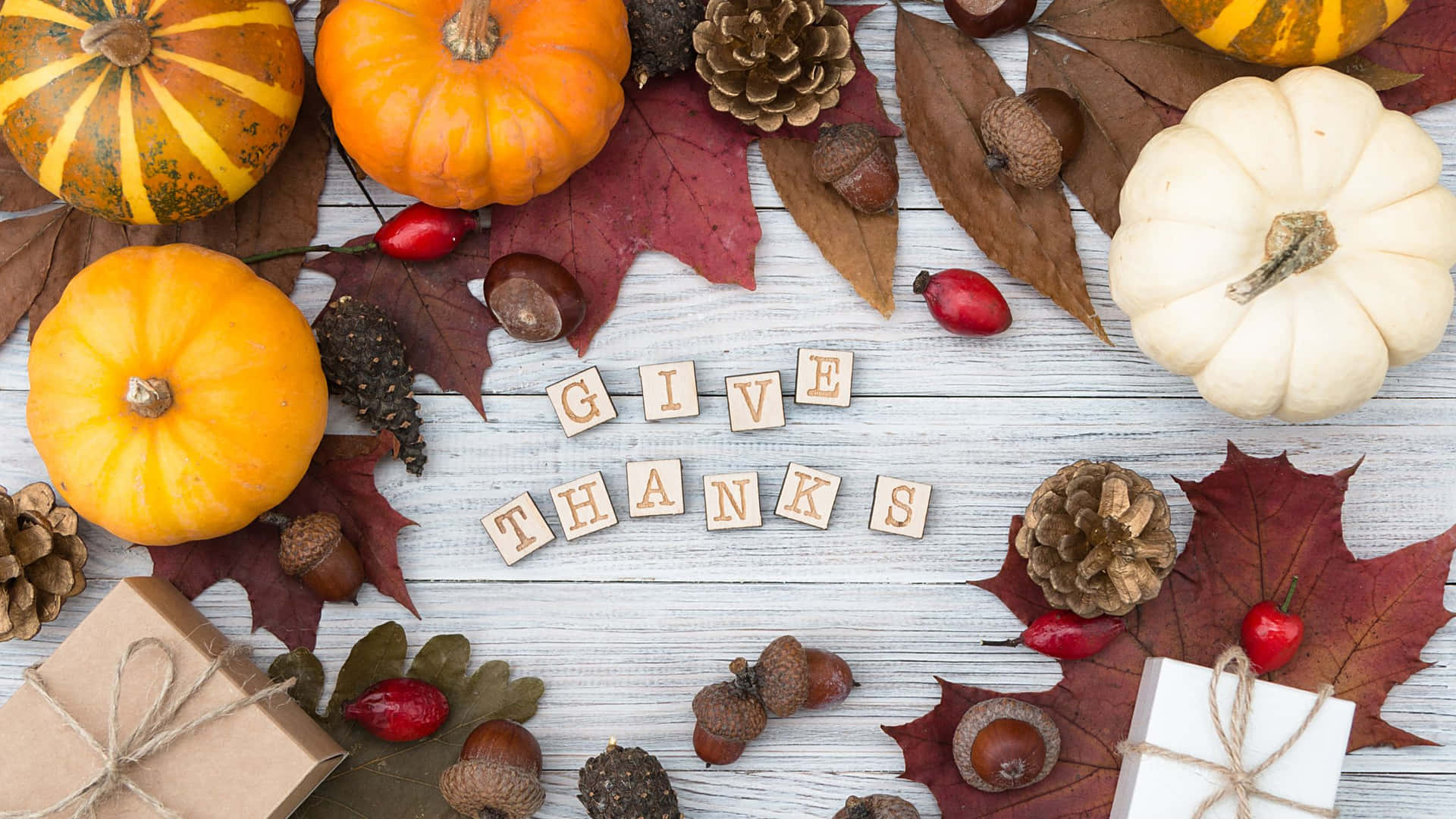 南瓜、松果和樹葉的秋季佈置，木塊拼出 give thanks。