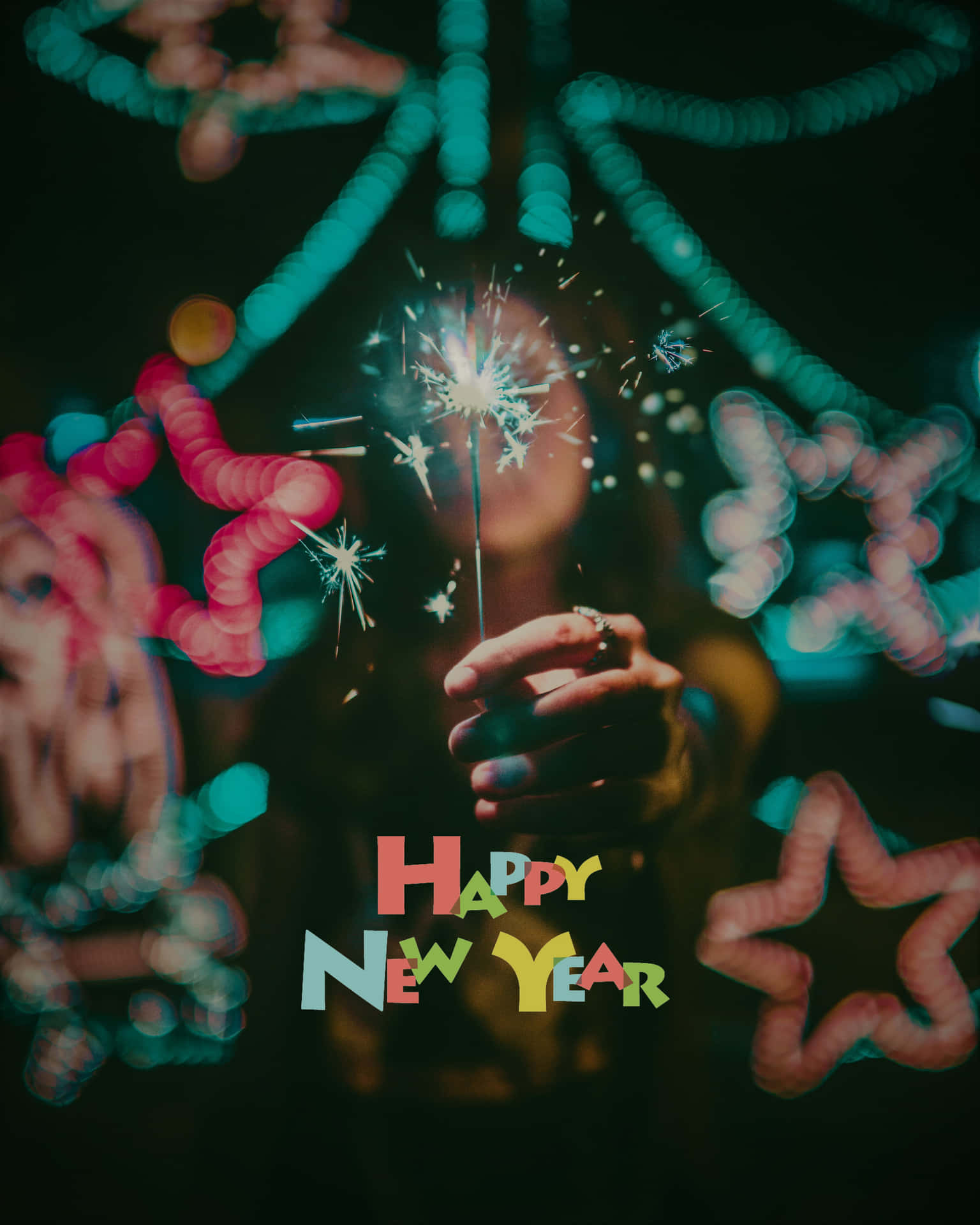 手拿著寫有「Happy New Year」字樣的煙花棒，背景有發光的星星燈光。