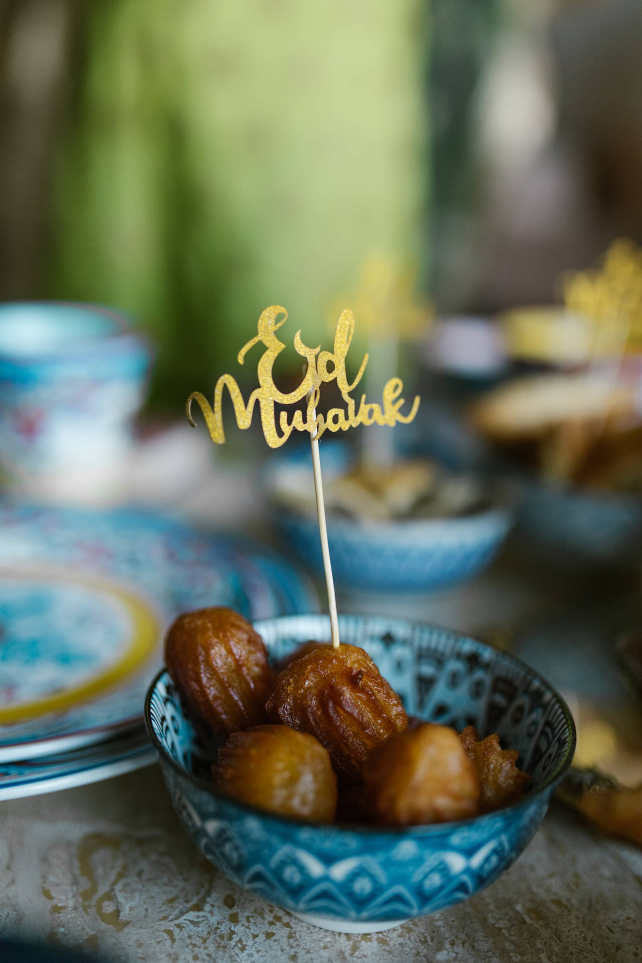 藍色圖案碗盛載炸麵糰球，配上金色 Eid Mubarak 標誌。
