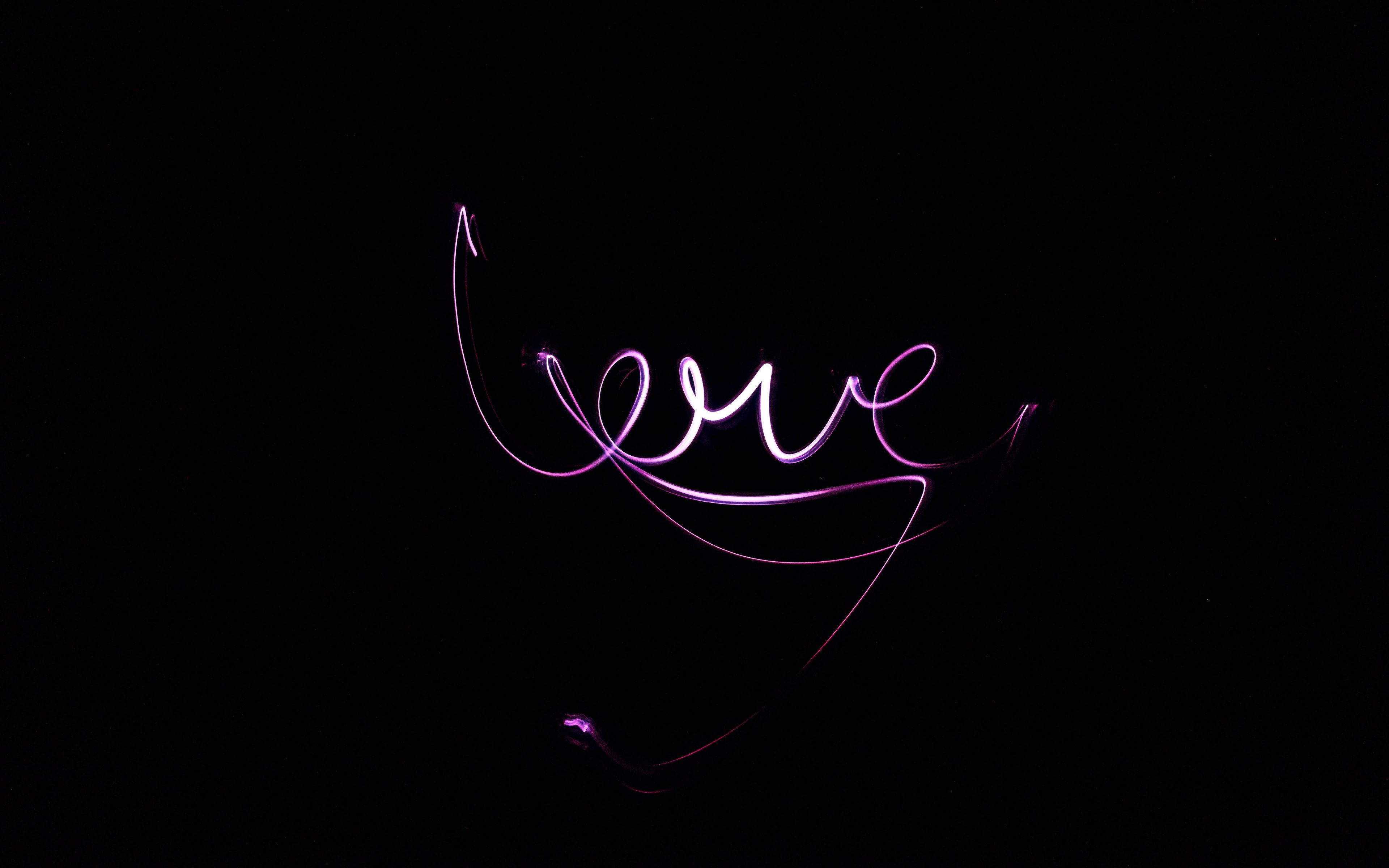 慶祝黑愛故事 壁紙 — 「love」這個詞以發光的紫色光軌寫在純黑色背景上。