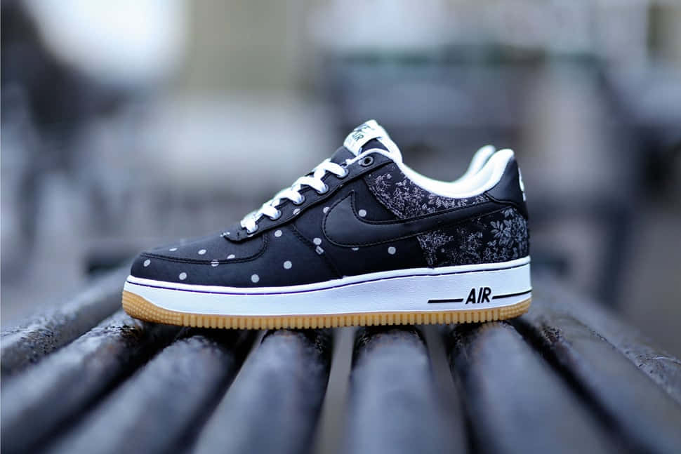 黑色Nike Air Force 1波鞋，帶白色圓點和花卉圖案，在木長凳上。
