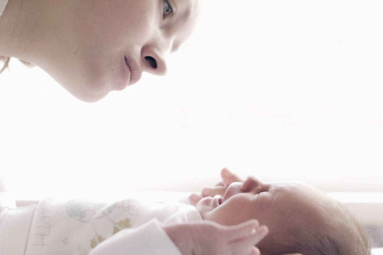 母親在柔和自然光線中溫柔地看著她的新生嬰兒。