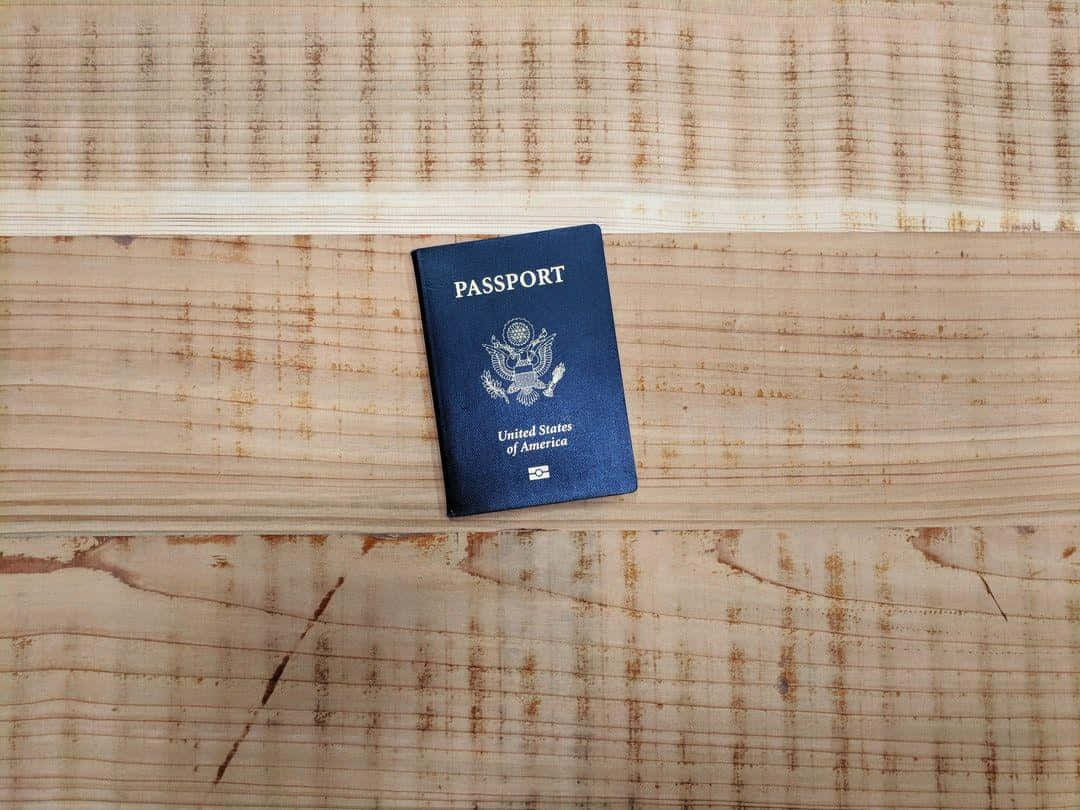 憑護照輕鬆旅行 壁紙 — 一本美國護照放在帶有天然木紋的紋理木質表面上。