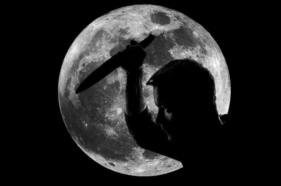 憤怒月夜剪影 壁紙 — 一個剪影人物在細節豐富的滿月背景下舉起一把刀，呈現鮮明的黑白對比。
