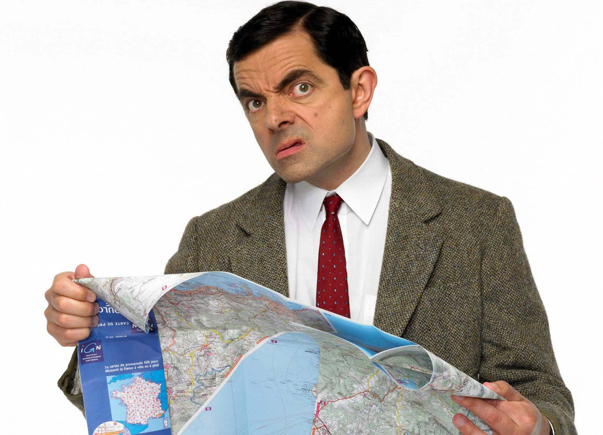 憨豆先生假期地圖 壁紙 — Mr. Bean 困惑地盯著一張皺巴巴的地圖，表情滑稽地困惑，背景是純白色。