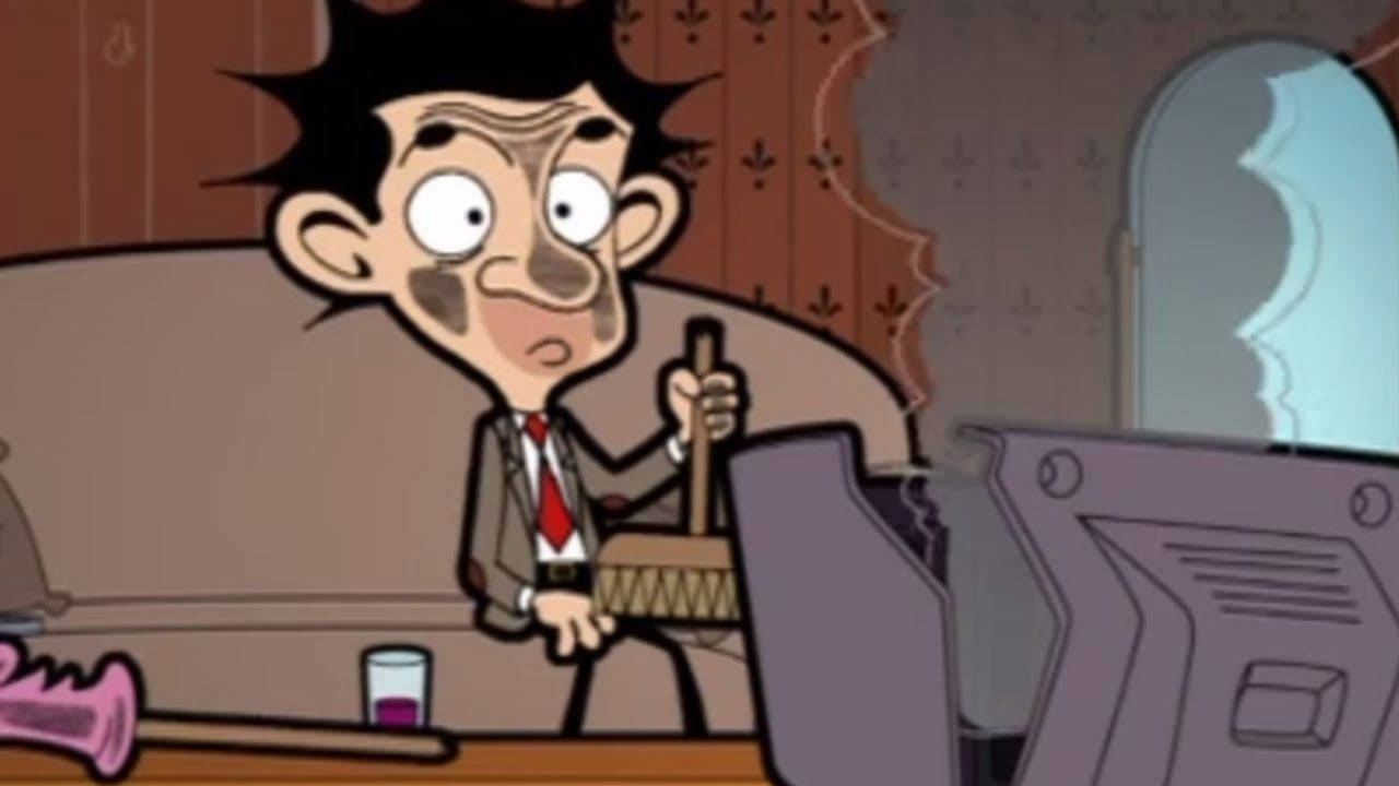 Mr. Bean 在雜亂的書桌前手持掃帚，表情驚訝。