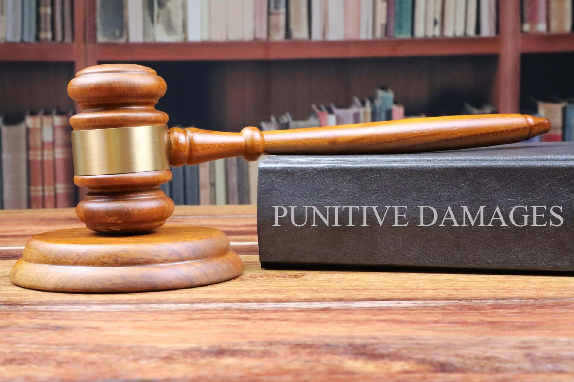 木槌和名為 punitive damages 的書在木桌上，後面有書架。