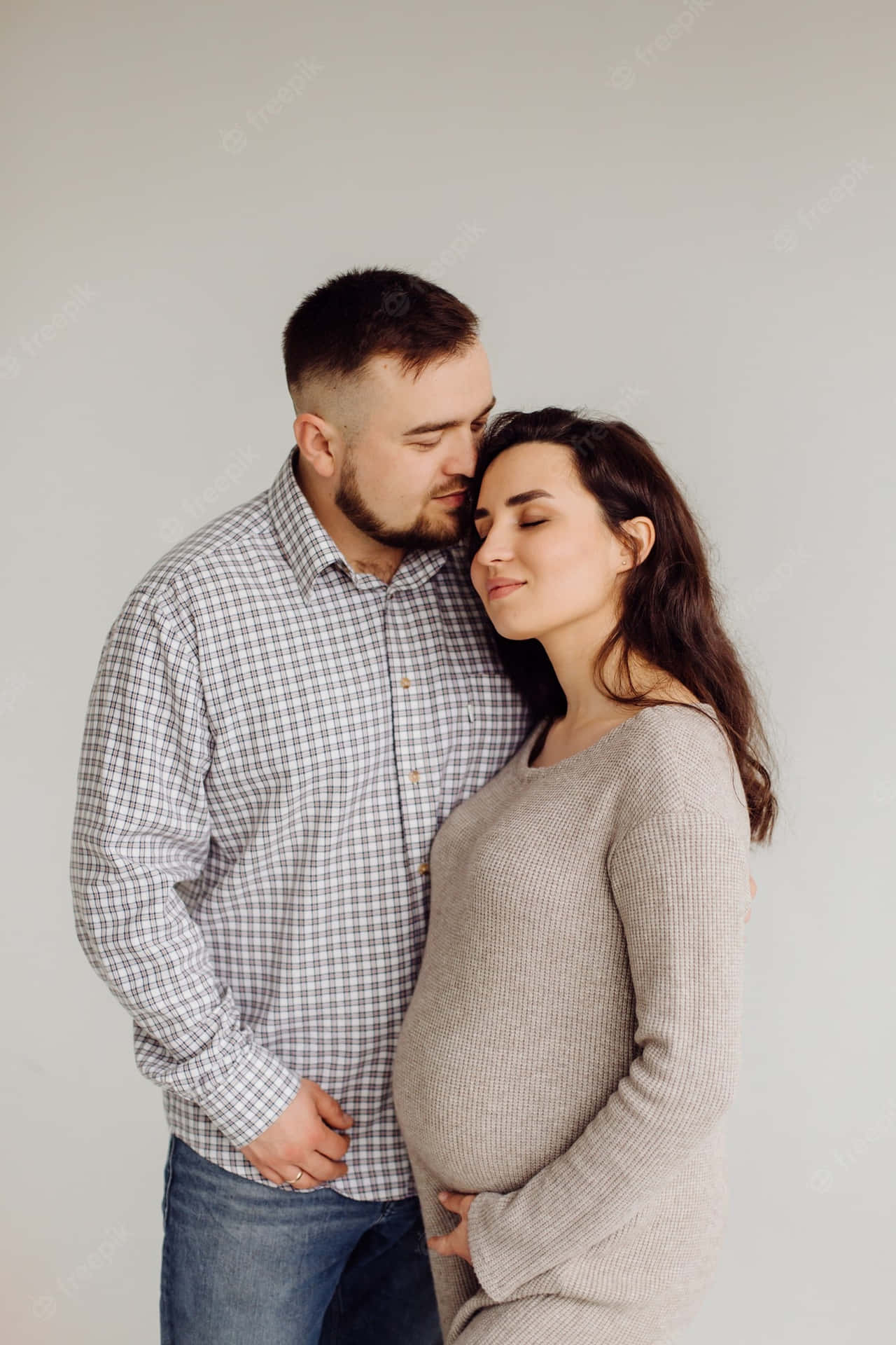 一個男人在充滿愛意的擁抱中親吻孕婦的額頭。