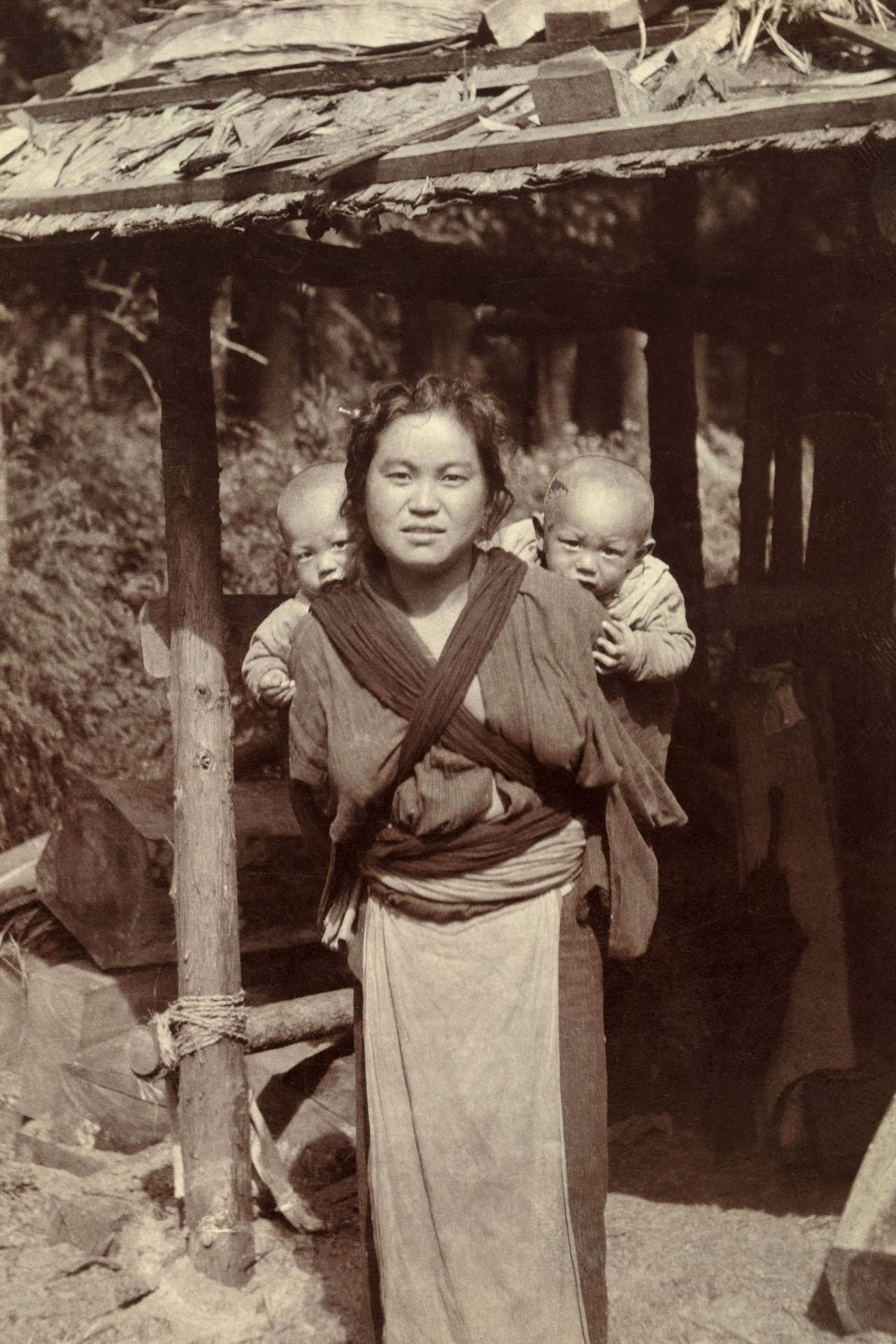 婦女在木棚下用傳統布包裹著兩個嬰兒。