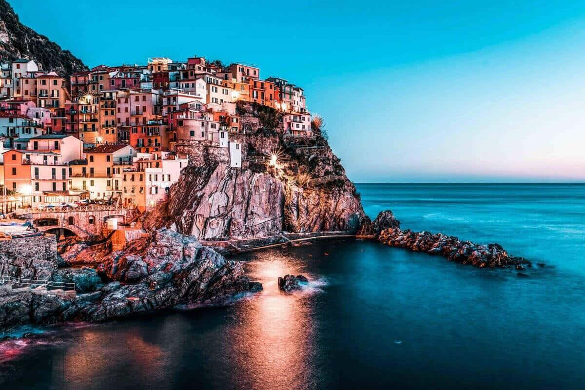 Italian Island 桌布 壁紙 — 懸崖村莊的鮮豔燈光在涼爽的暮色海洋和天空中溫暖地閃耀。