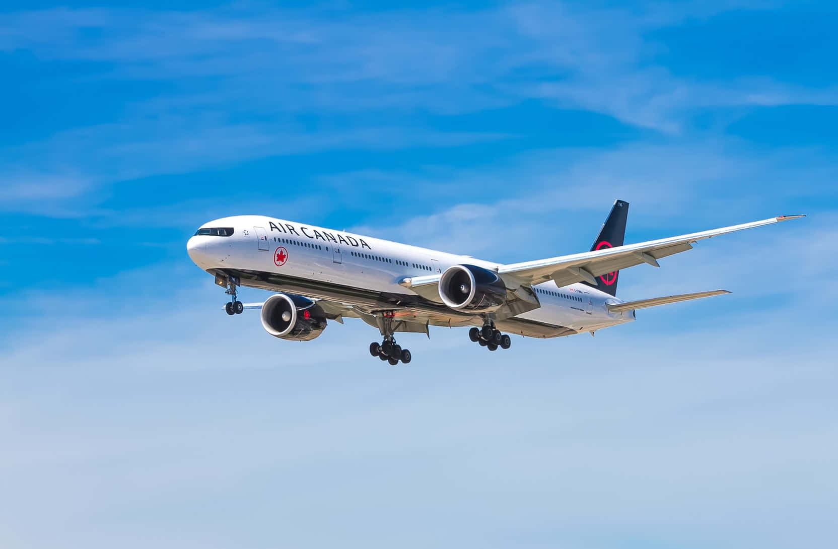 懸浮飛機圖像 壁紙 — 一架加拿大航空飛機放下起落架，在晴朗藍天和縷縷白雲中翱翔。