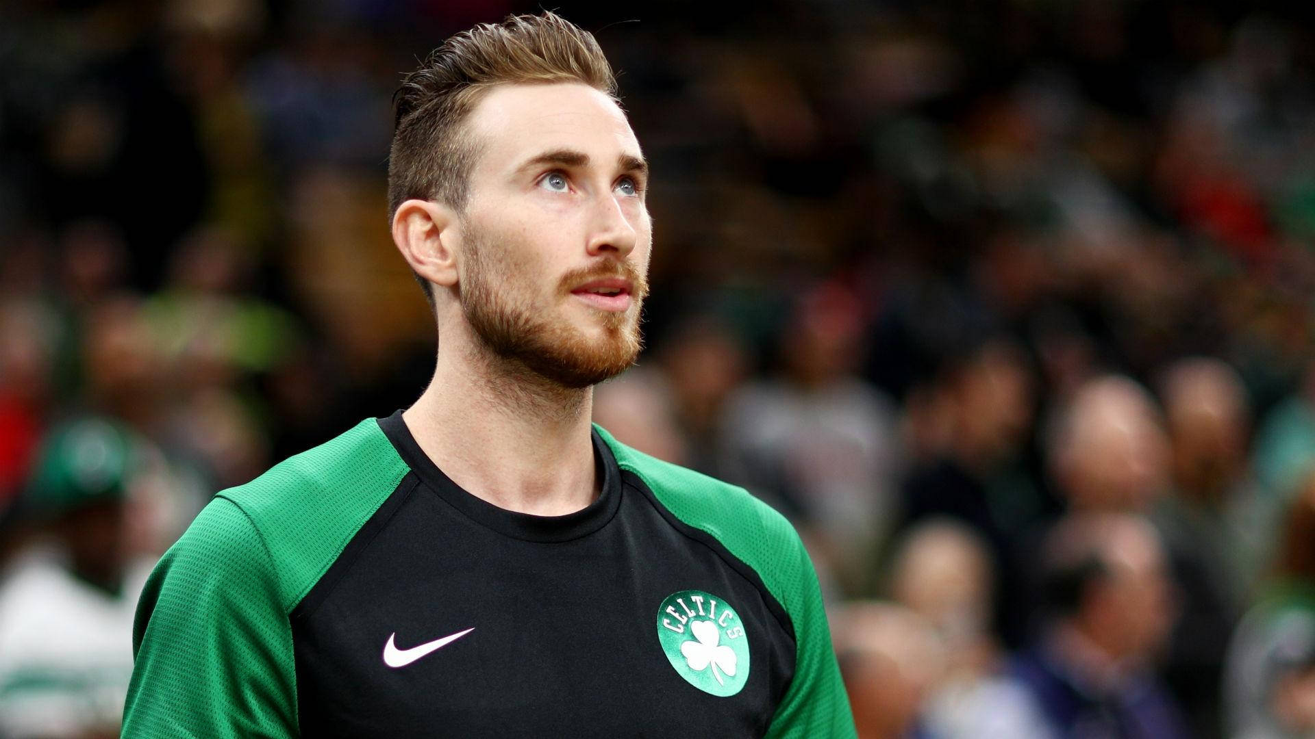 戈登·海沃德 NBA 預賽 2019 壁紙 — 一位專注的籃球運動員身穿綠色和黑色的塞爾特人球衣，在比賽中向上凝視，身後是模糊的人群。