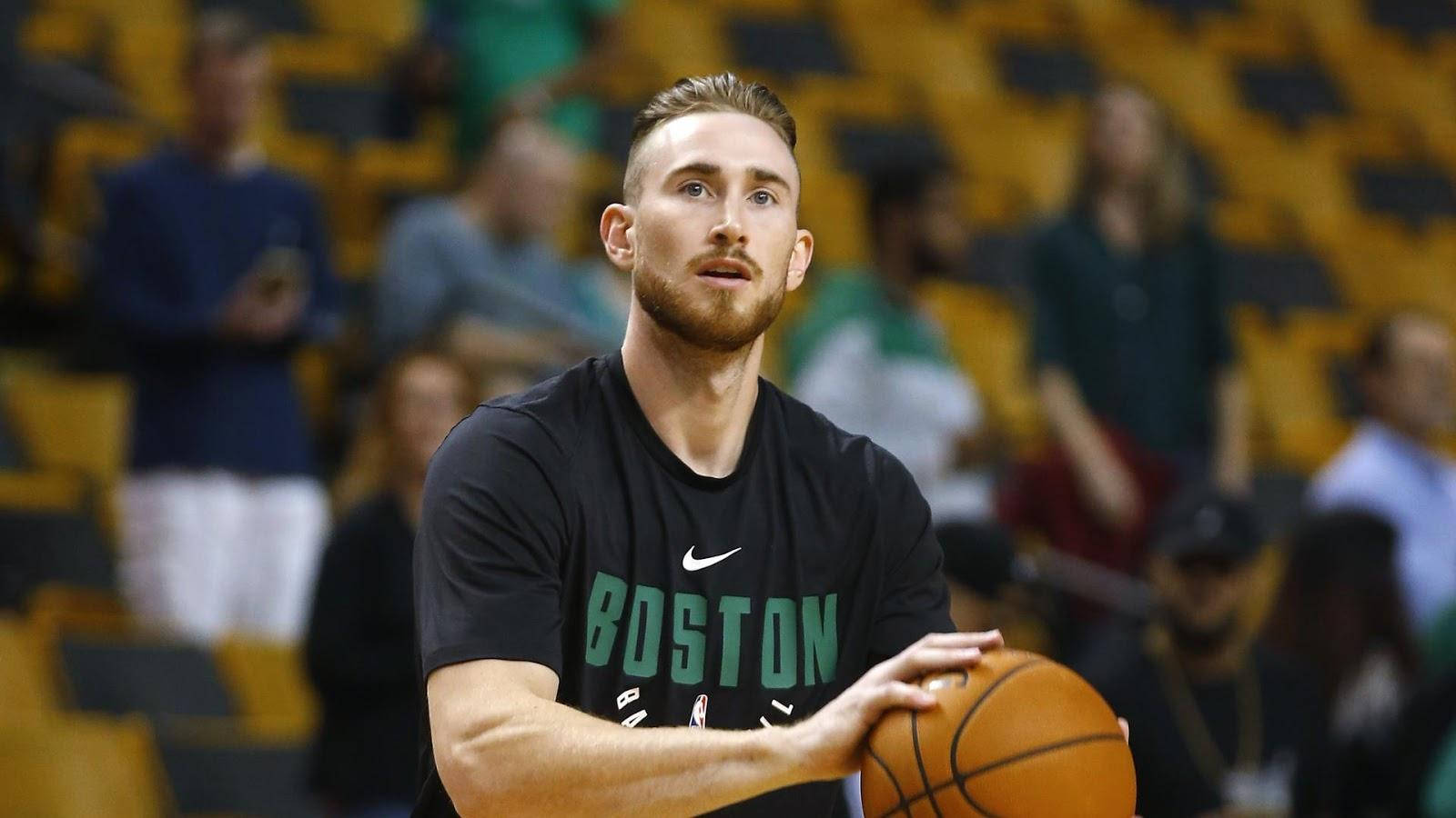 戈登·海沃德 NBA 預賽 2017 壁紙 — 一位專注的籃球運動員身穿波士頓球衣，在練習中持球，背後黃色座位上的觀眾模糊不清。