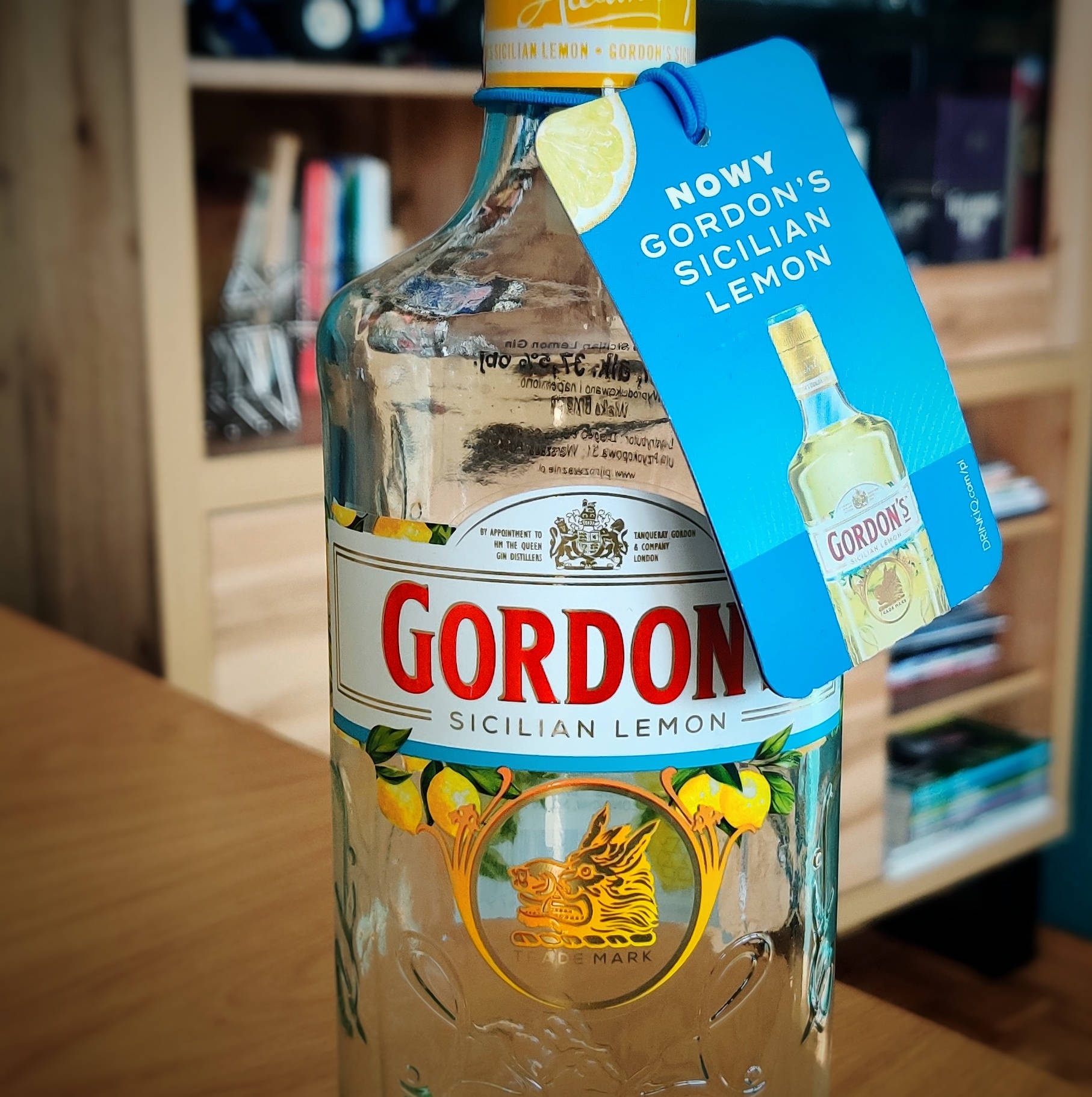 Gordon's Sicilian Lemon氈酒瓶，帶藍色標籤，放在木桌上。