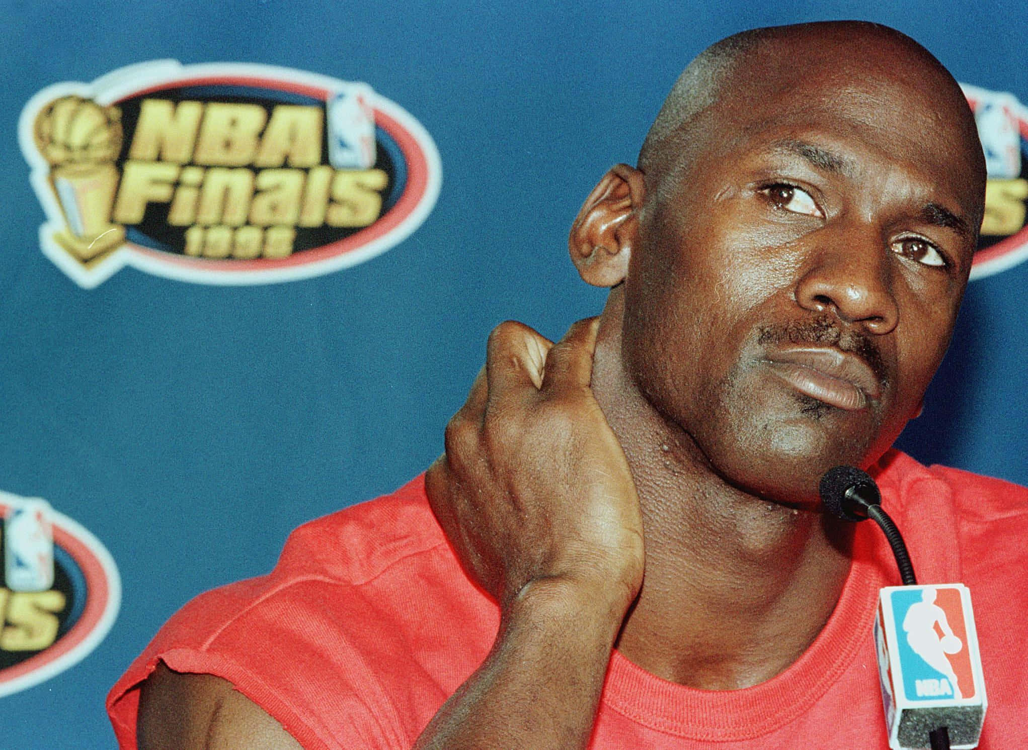 '成就與成功' - 迈克尔·乔丹 壁紙 — 米高佐敦身穿紅色襯衫，在1995年NBA總決賽記者會上表情嚴肅地抓脖子。